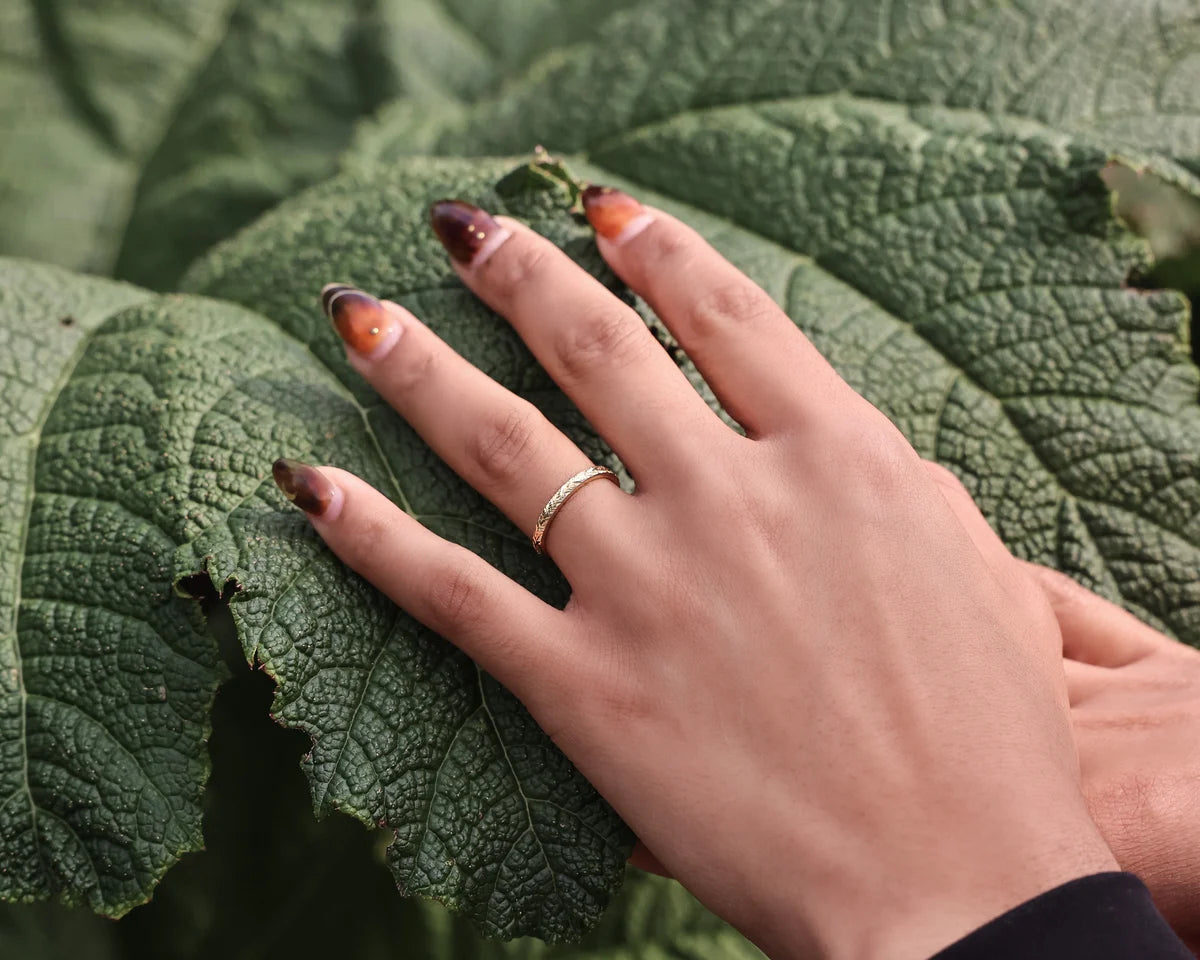 Laurel leaf engraved wedding ring worn on hand with green botanical styling