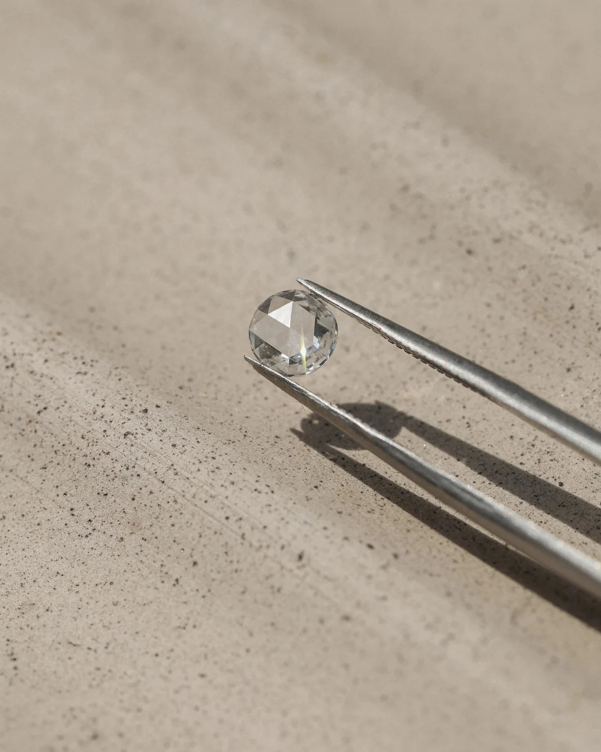 Loose rose-cut white diamond held with tweezers