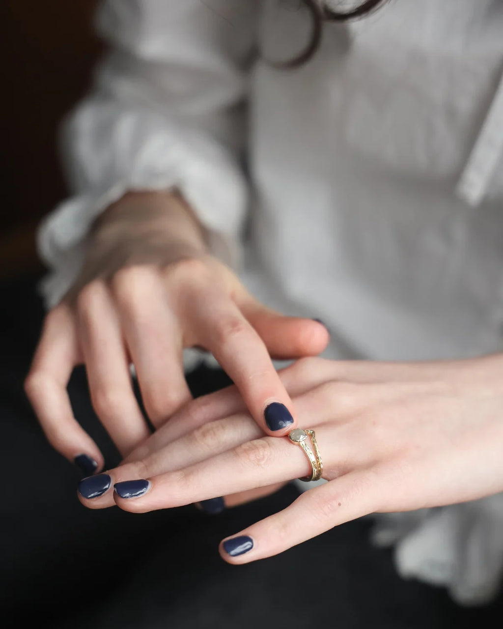 Pale grey rose-cut diamond ring worn on hand with dark nails
