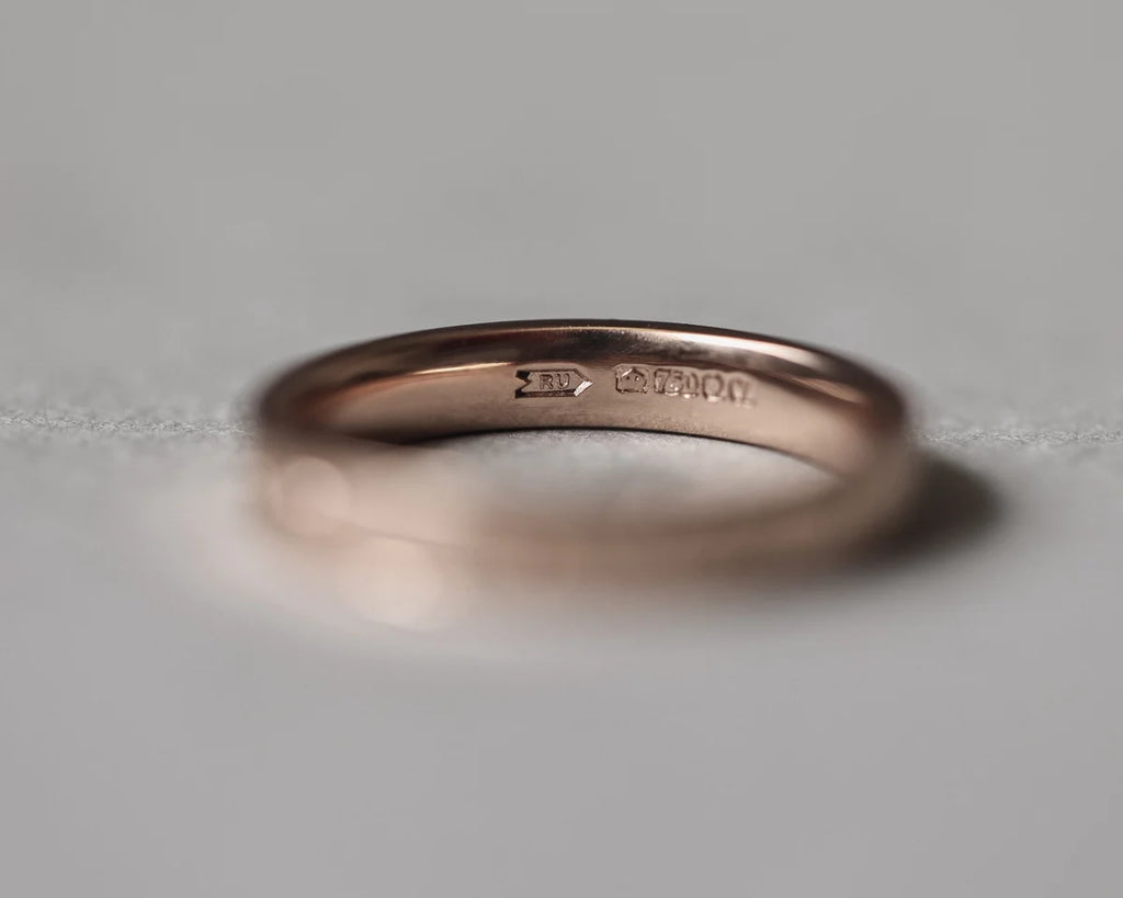 Rose gold ring with visible branding on a gray background