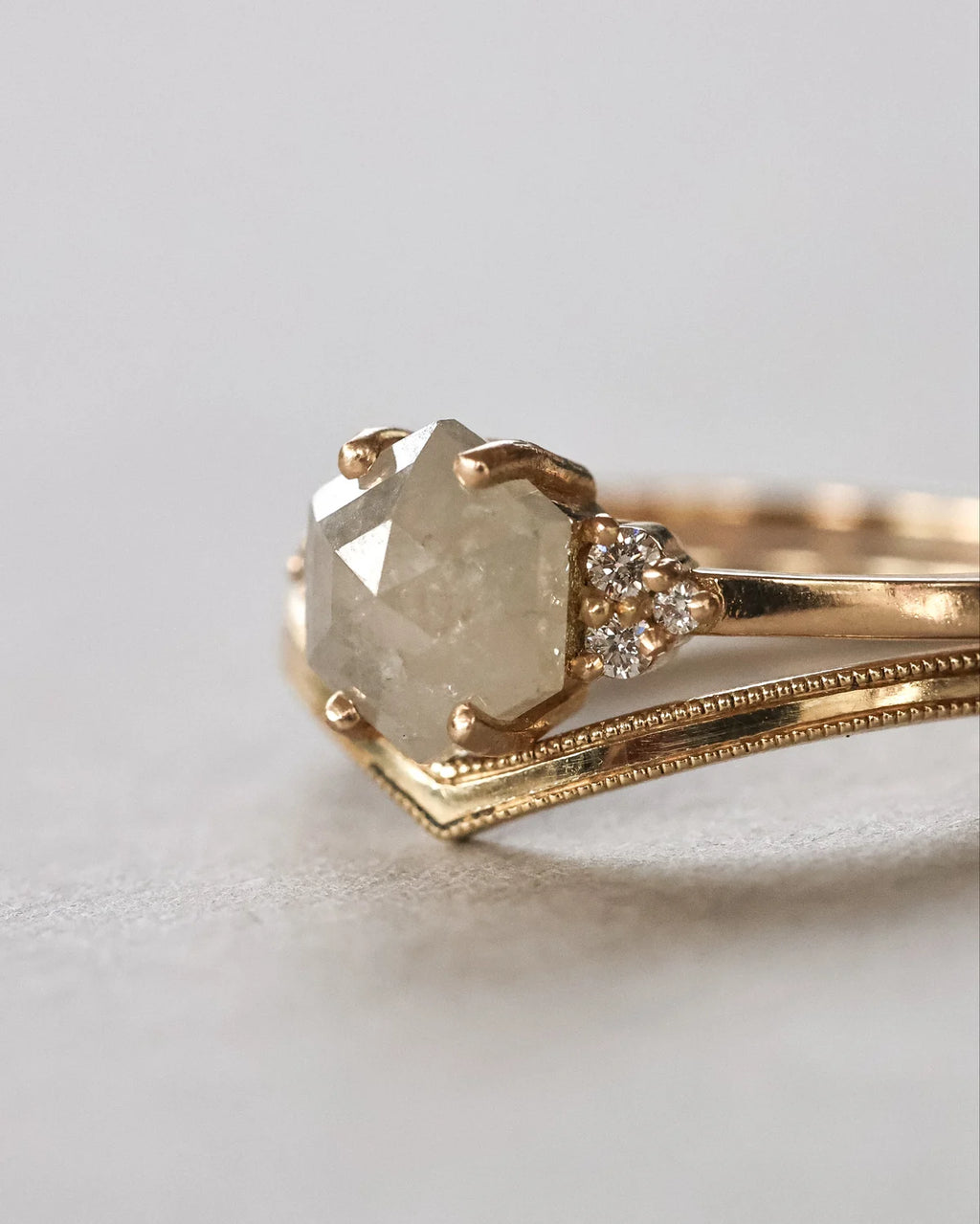 Gold ring with a large diamond and smaller diamonds on a light gray background