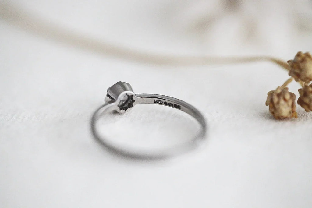 Silver ring with a small diamond on a light background