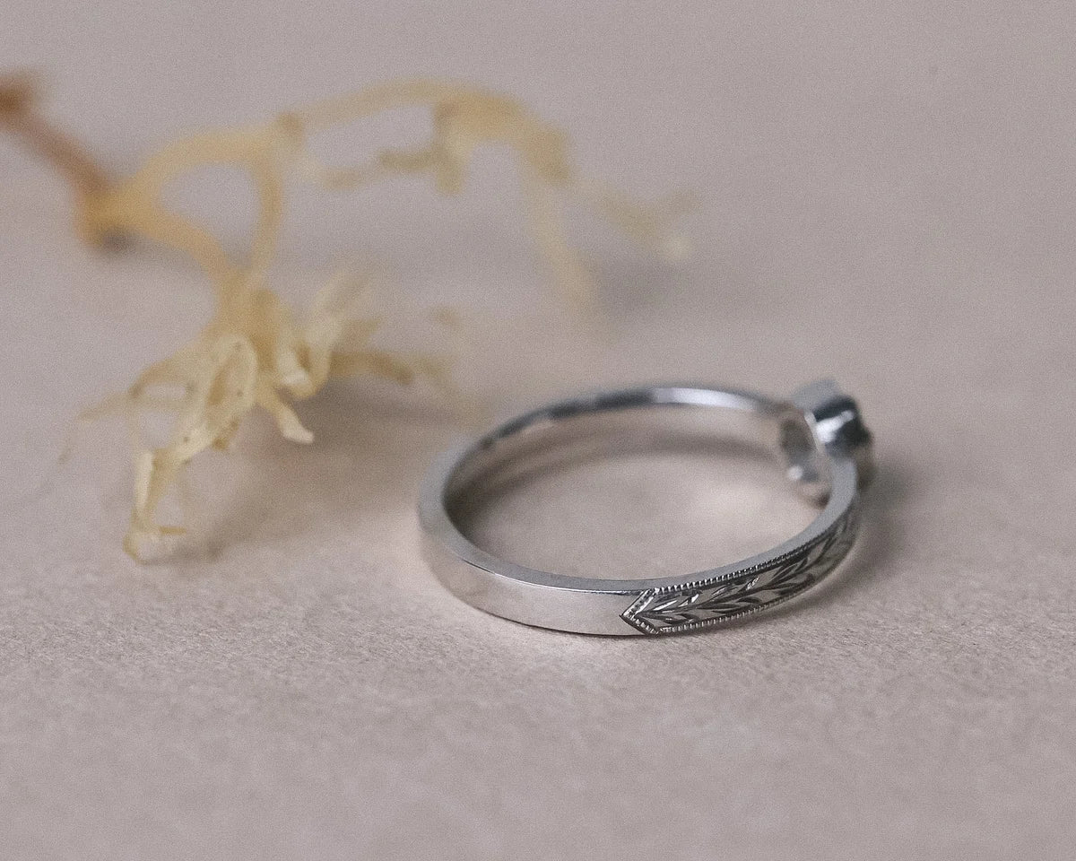Delicate platinum engagement ring with hand engraved band