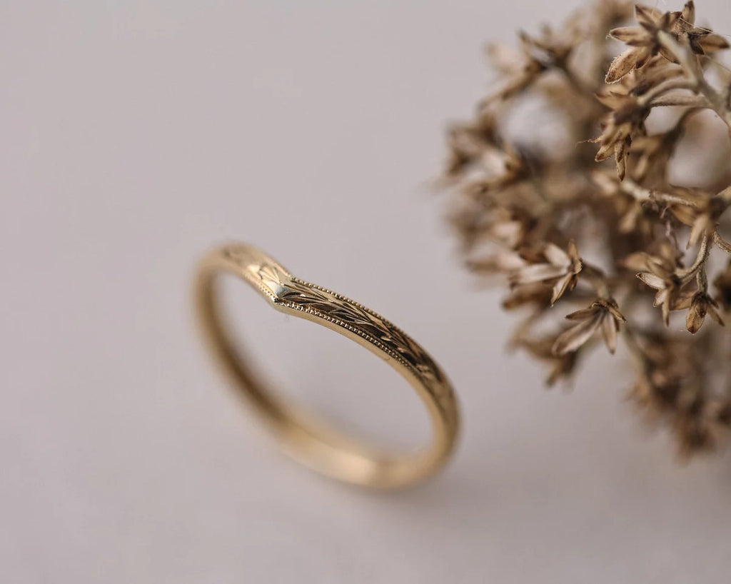 Angled close-up of handmade olive leaf and milled edge wishbone ring
