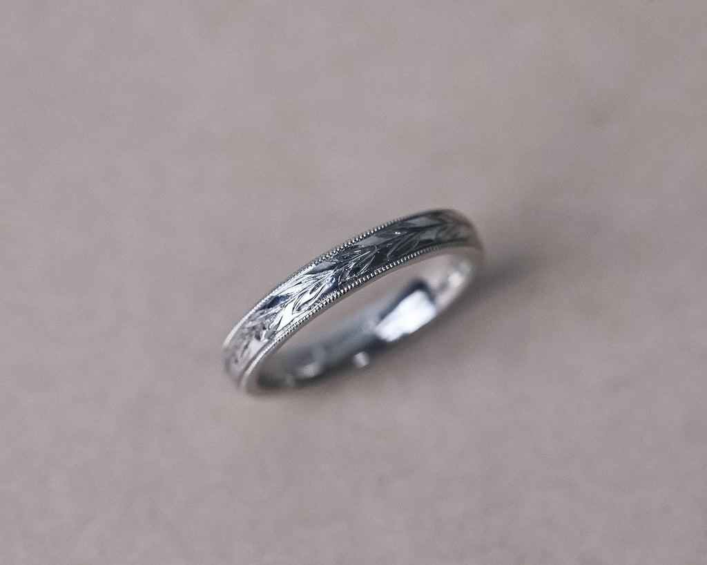 Angled view of platinum olive leaf and milled edge wedding ring
