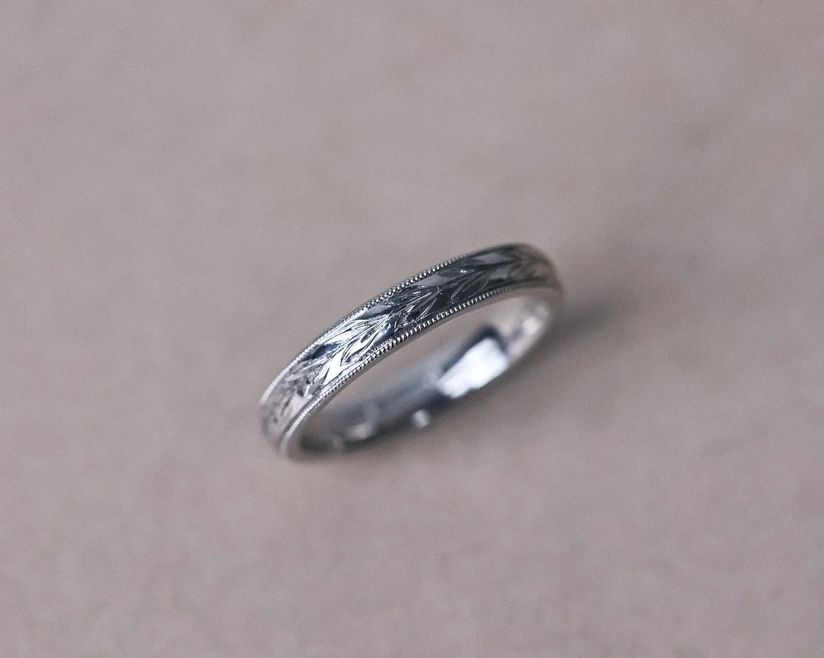 Angled view of platinum olive leaf engraved wedding ring