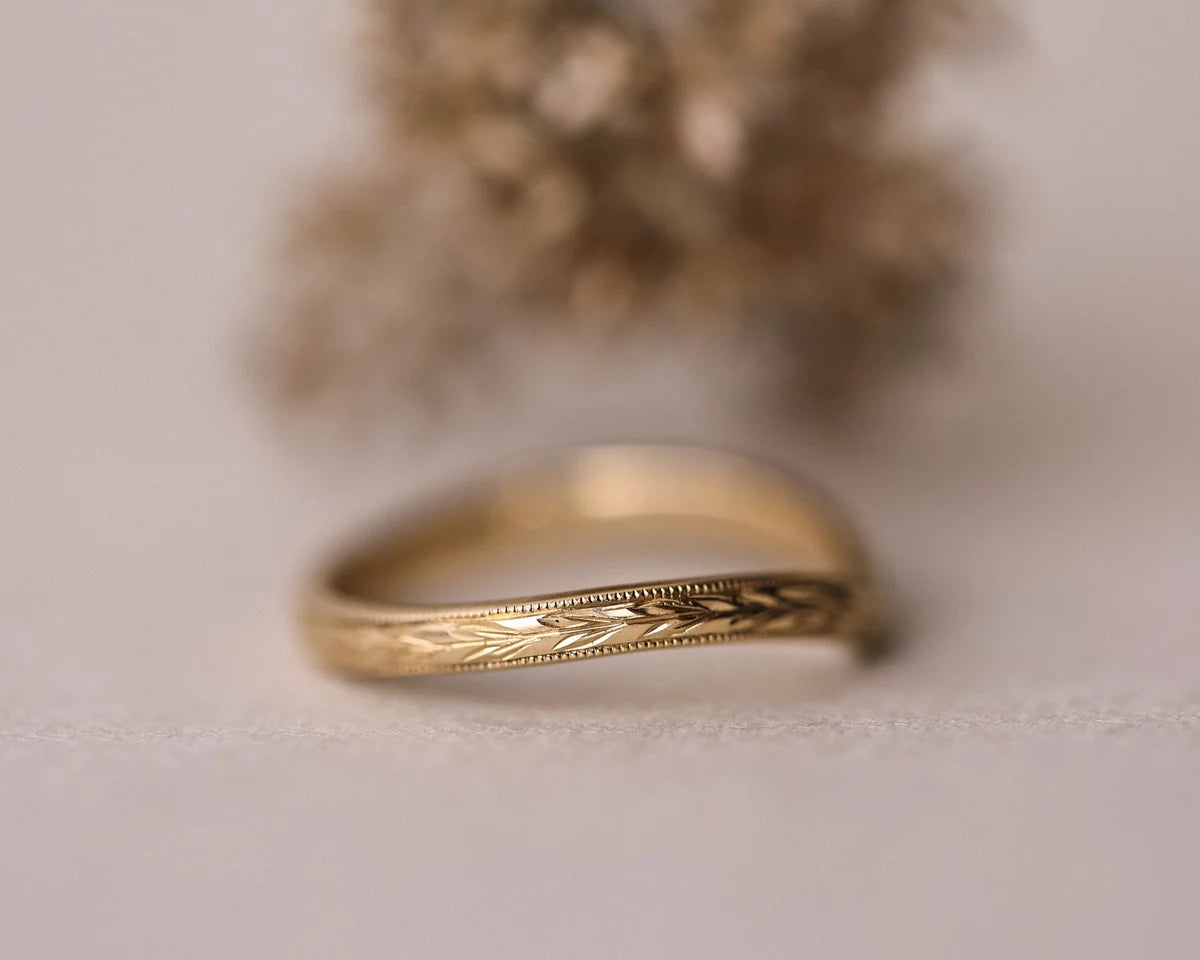 Low front view of olive leaf and milled edge wishbone ring in yellow gold