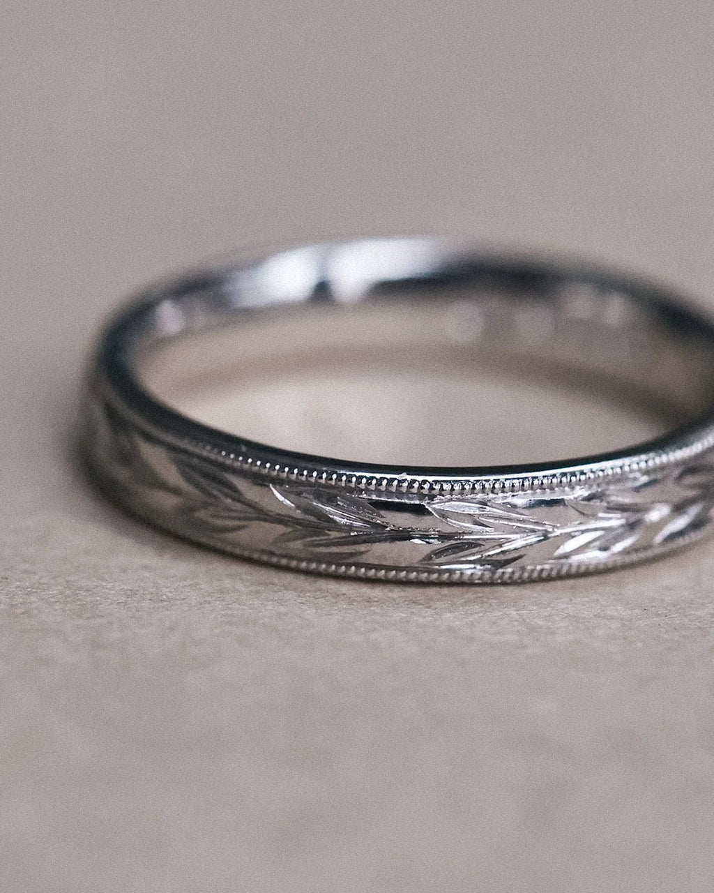 Close-up of olive leaf engraving and milled edge on platinum band
