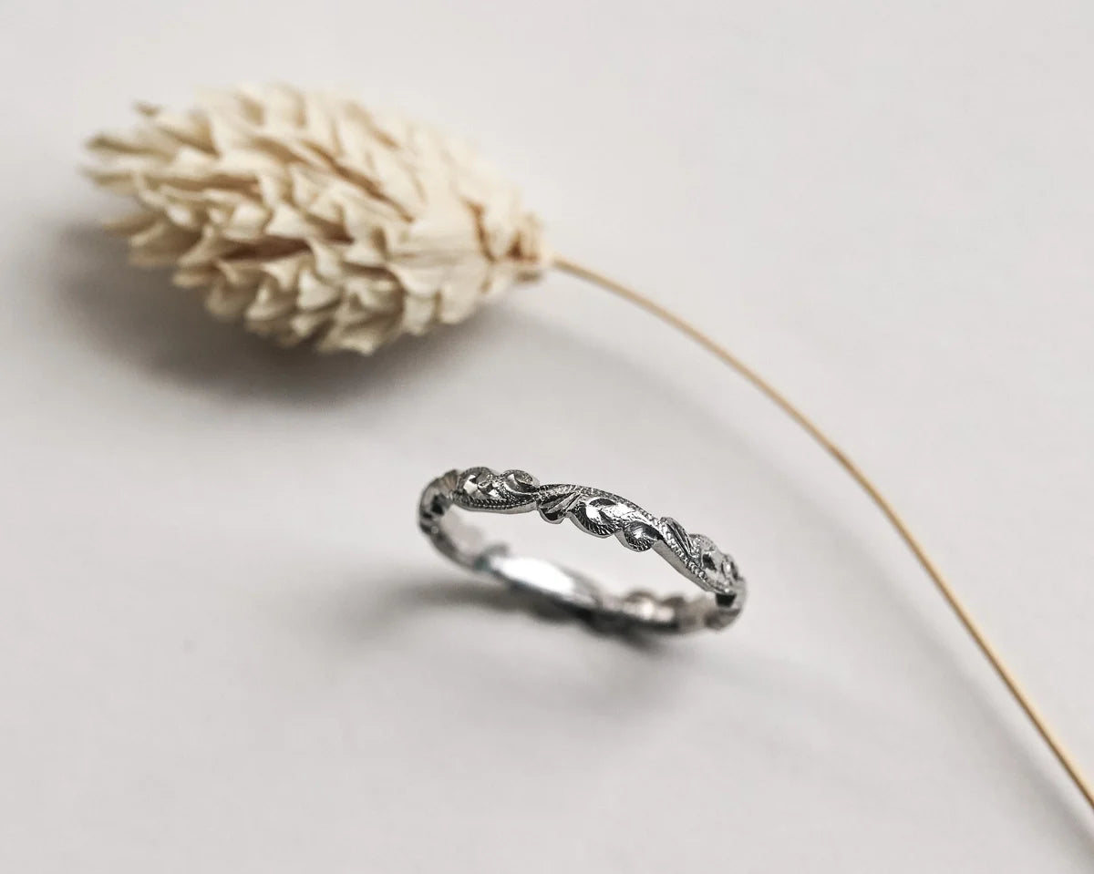 Angled view of platinum floral carved wedding ring with botanical styling
