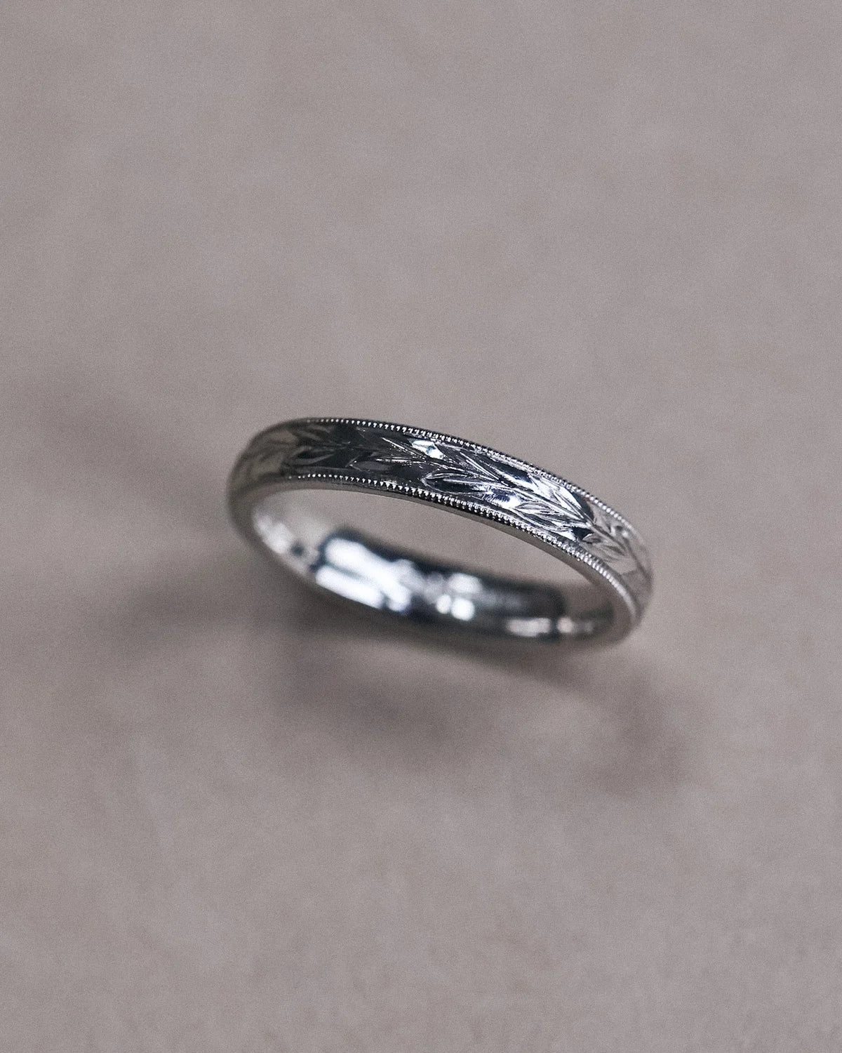 Side view of olive leaf engraved platinum ring with milled edge
