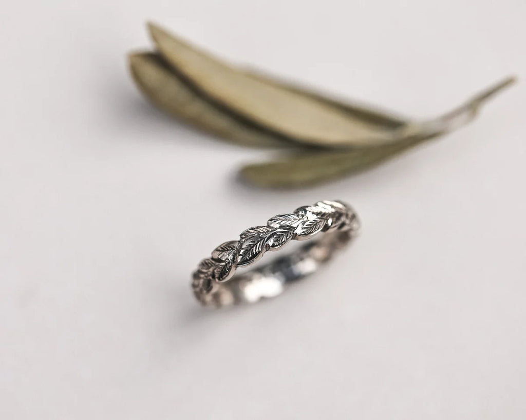 close up laurel leaf carving detail on white gold ring 4mm band