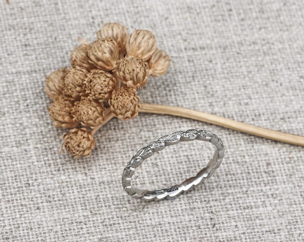 Silver ring with intricate design on a textured fabric background
