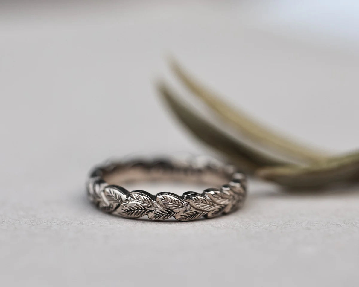close up laurel leaf carving detail on white gold ring 4mm band