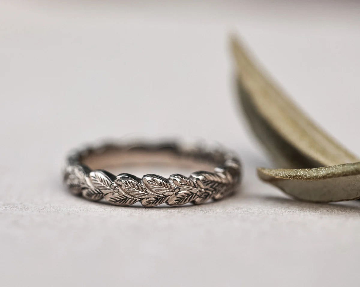 close up laurel leaf carving detail on white gold ring 4mm band