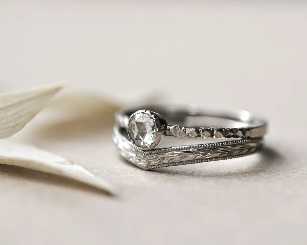  Close-up of platinum wishbone wedding ring paired with rose-cut diamond ring