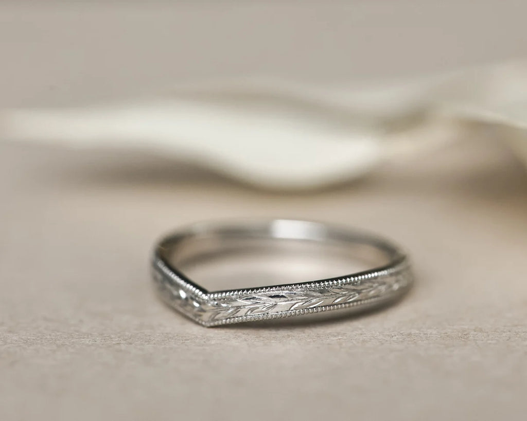 Silver ring with intricate design on a beige fabric background