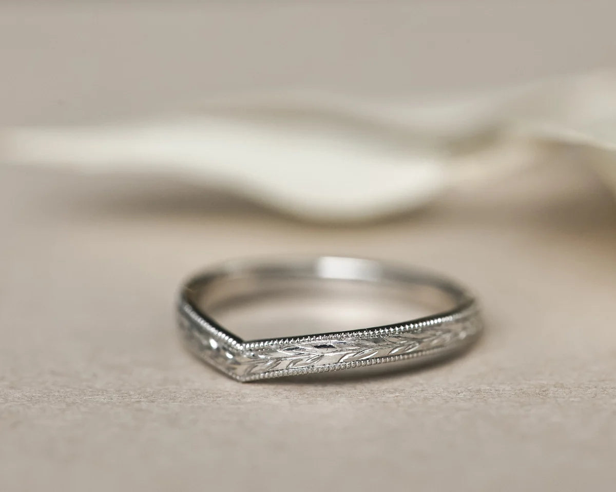 Silver ring with intricate design on a beige fabric background