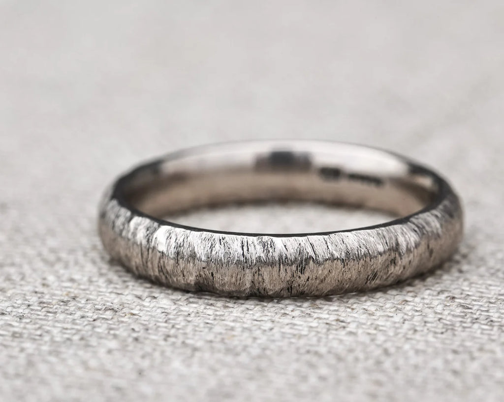 Silver ring with a textured band on a textured gray background