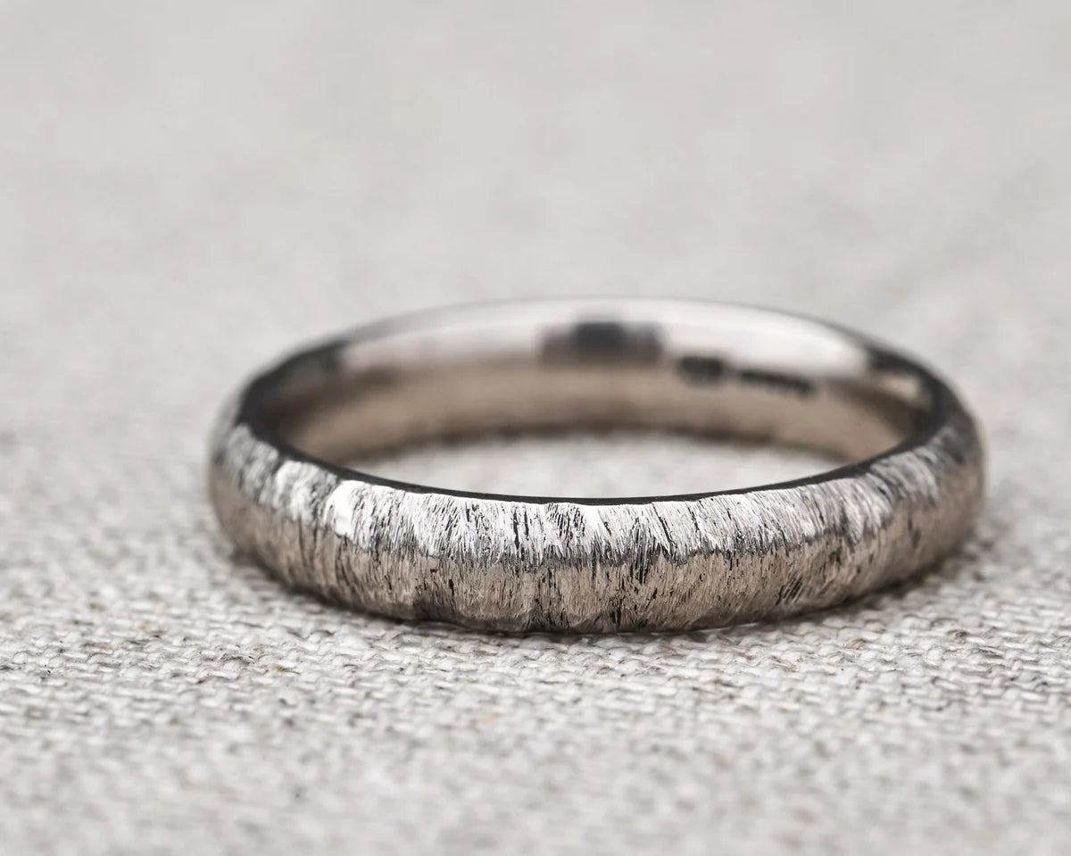 Silver ring with a textured band on a textured gray background