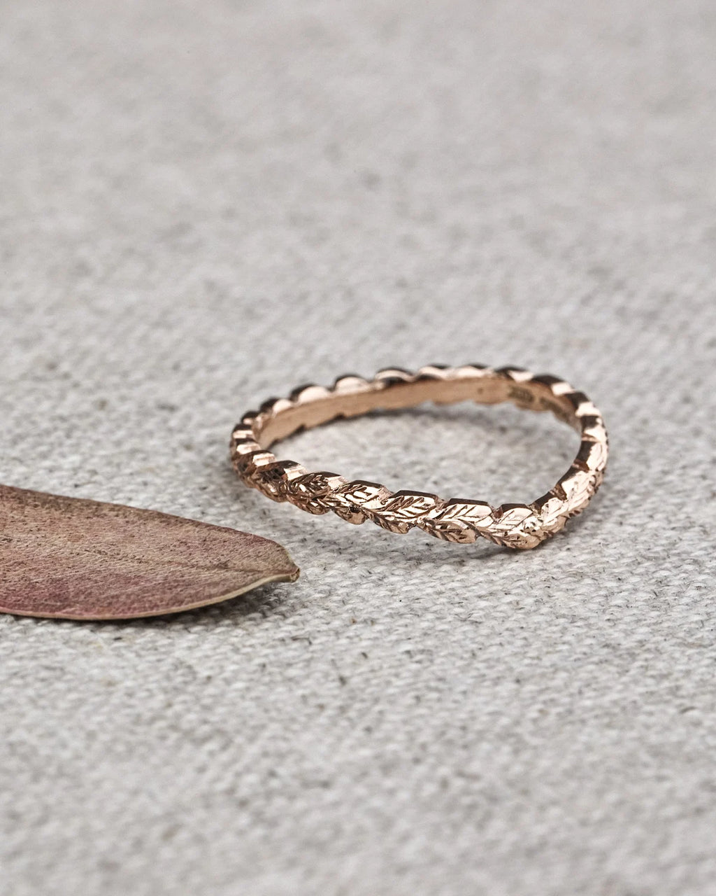 close up laurel leaf carving on rose gold wedding ring textured band