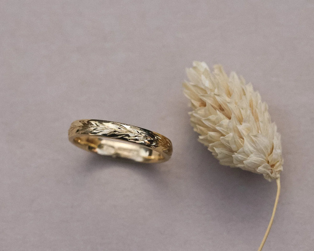 Close-up of 18ct yellow gold olive leaf engraved wedding ring