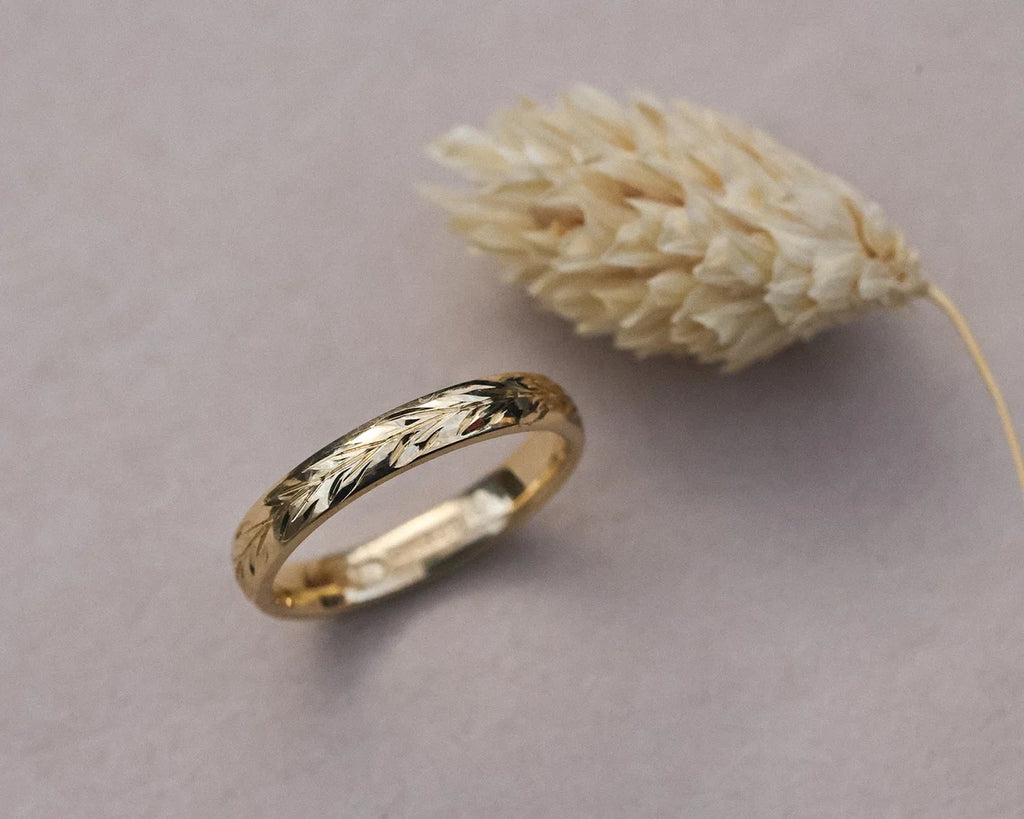 Angled view of 18ct yellow gold olive leaf engraved wedding ring