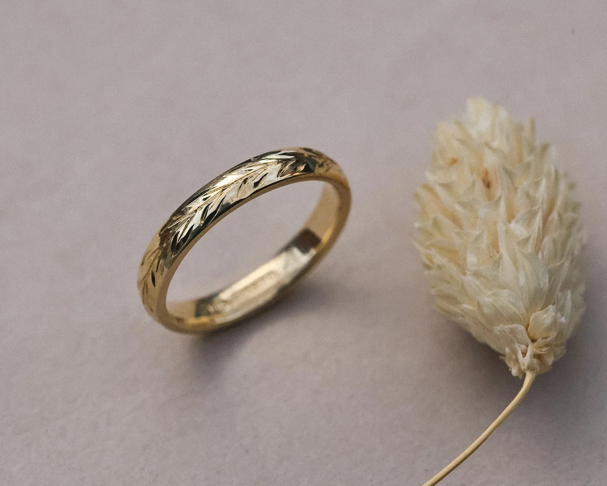 Side profile of hand engraved olive leaf wedding ring in yellow gold