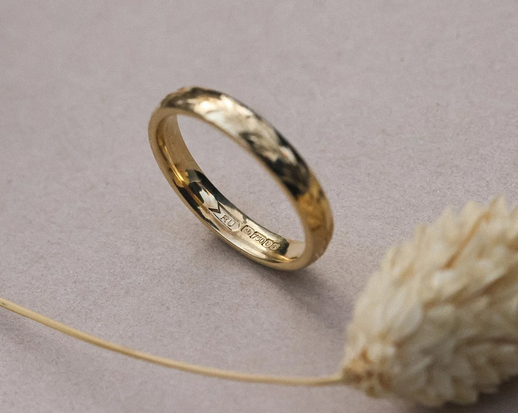 Angled close-up of 18ct yellow gold olive leaf engraved band