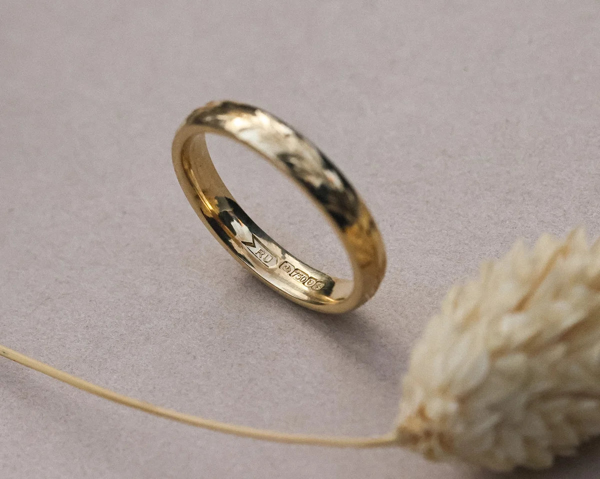 Angled close-up of 18ct yellow gold olive leaf engraved band