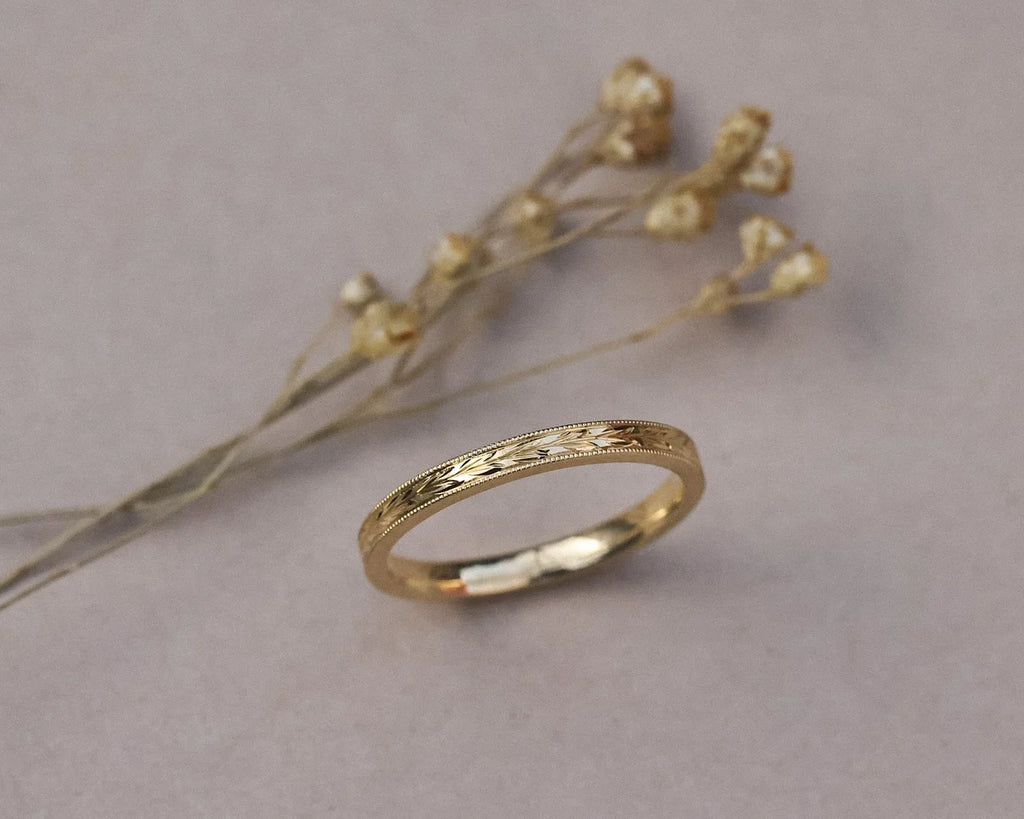 Angled view of 18ct yellow gold olive leaf and milled edge wedding ring