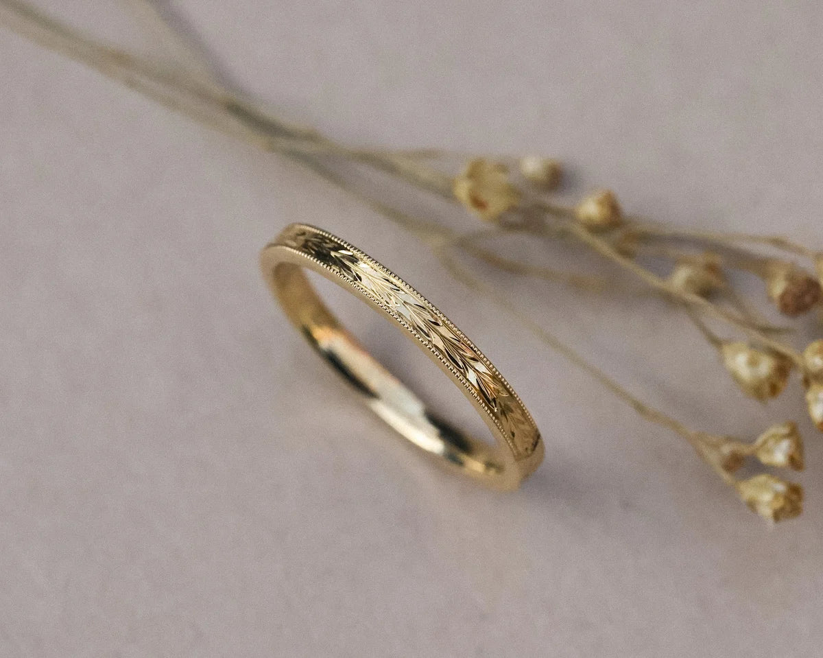 Side view of 2mm yellow gold flat court ring with olive leaf engraving