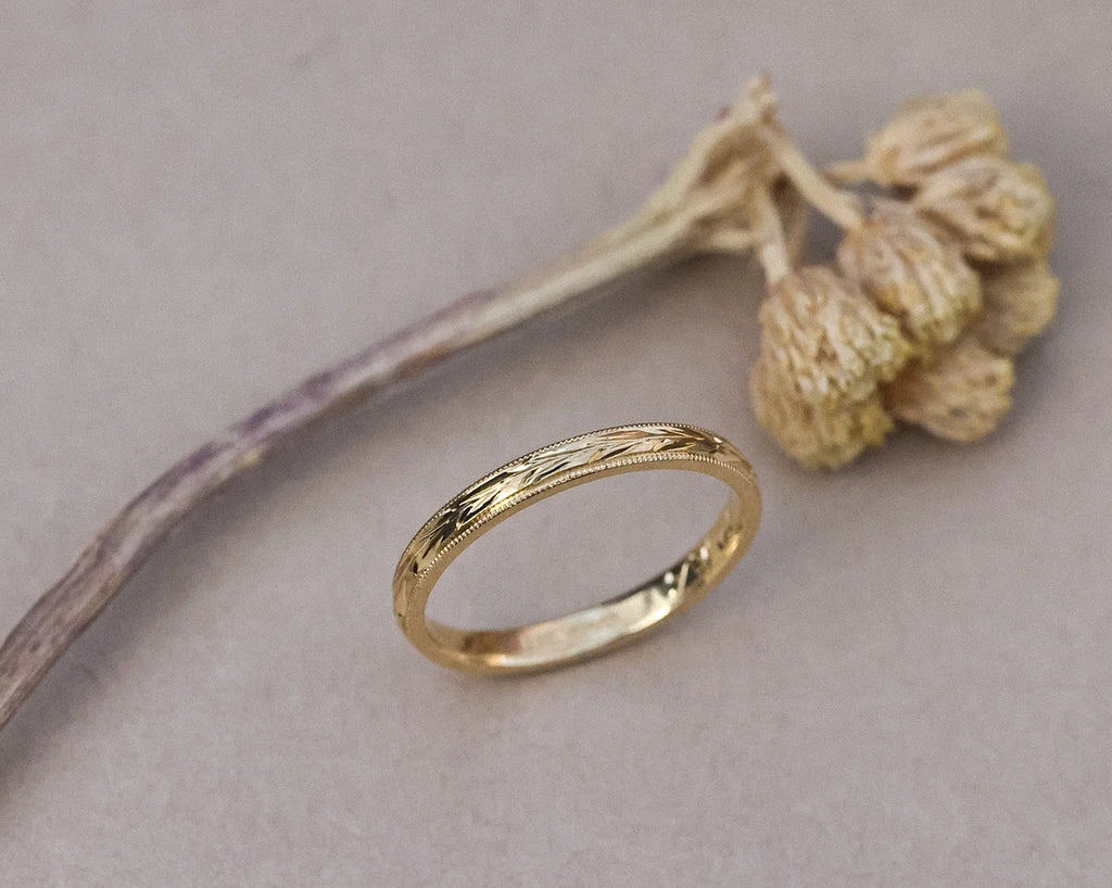 Angled view of yellow gold olive leaf ring with dried botanical detail