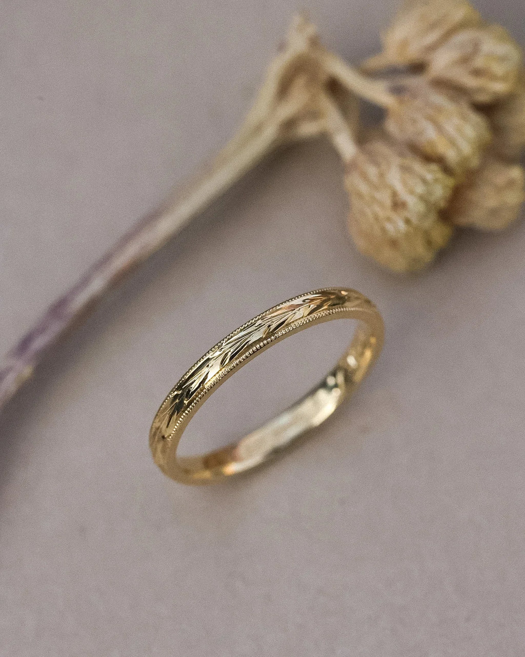 18ct yellow gold olive leaf wedding ring styled with dried flowers
