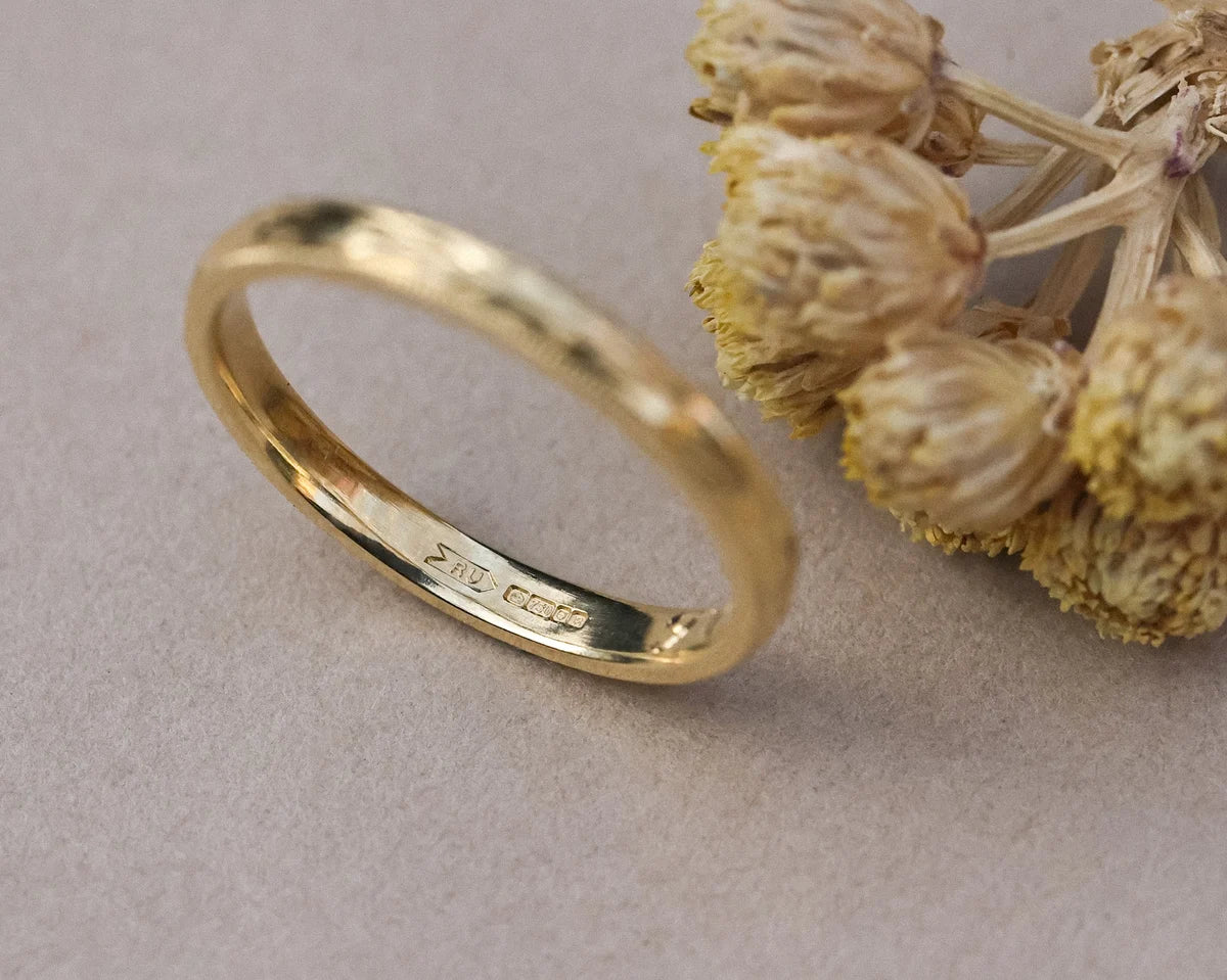 Close-up of hand engraved olive leaf detail on yellow gold band