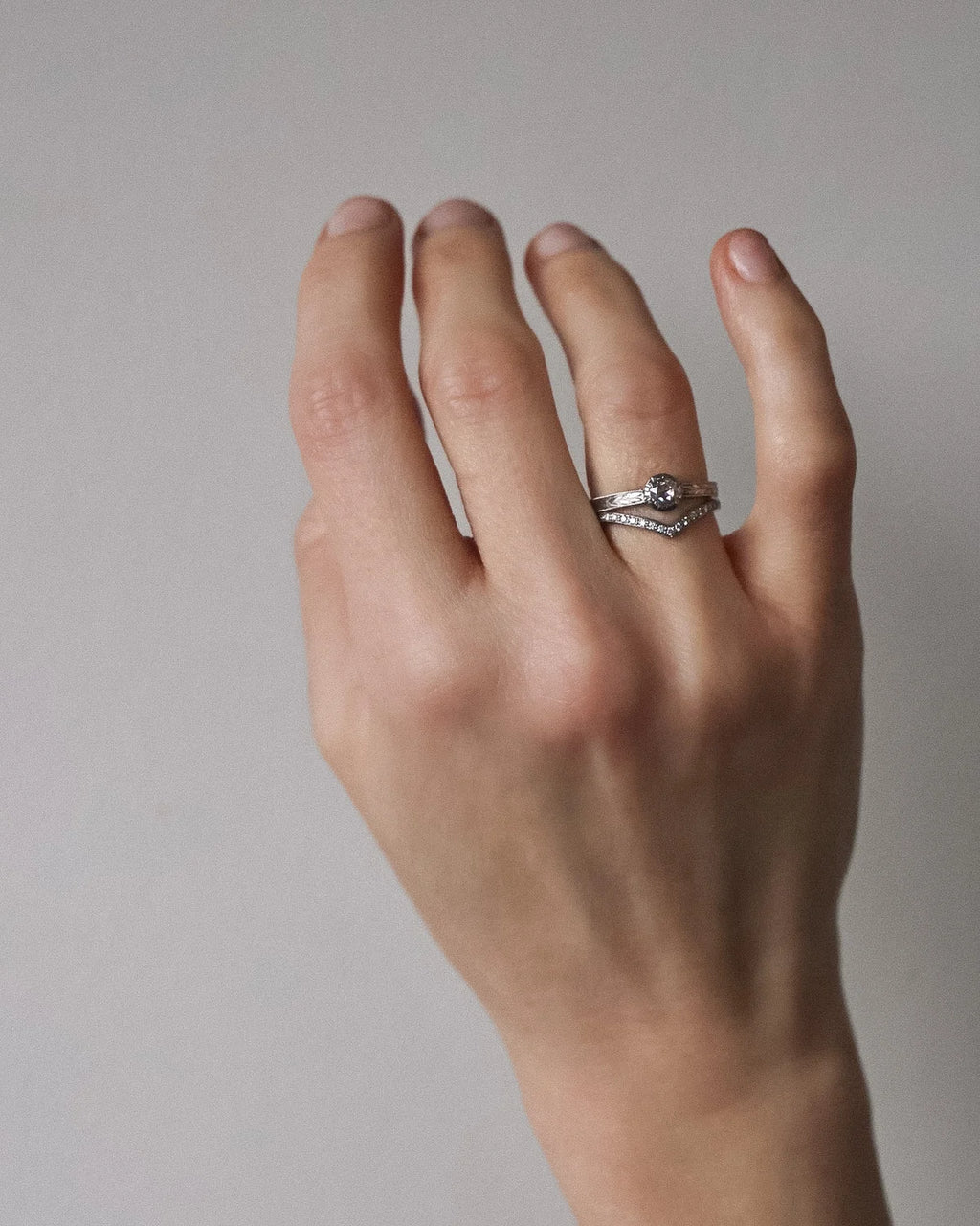 Woman wearing a handmade platinum rose-cut diamond engagement ring with matching pavé wishbone wedding band.
