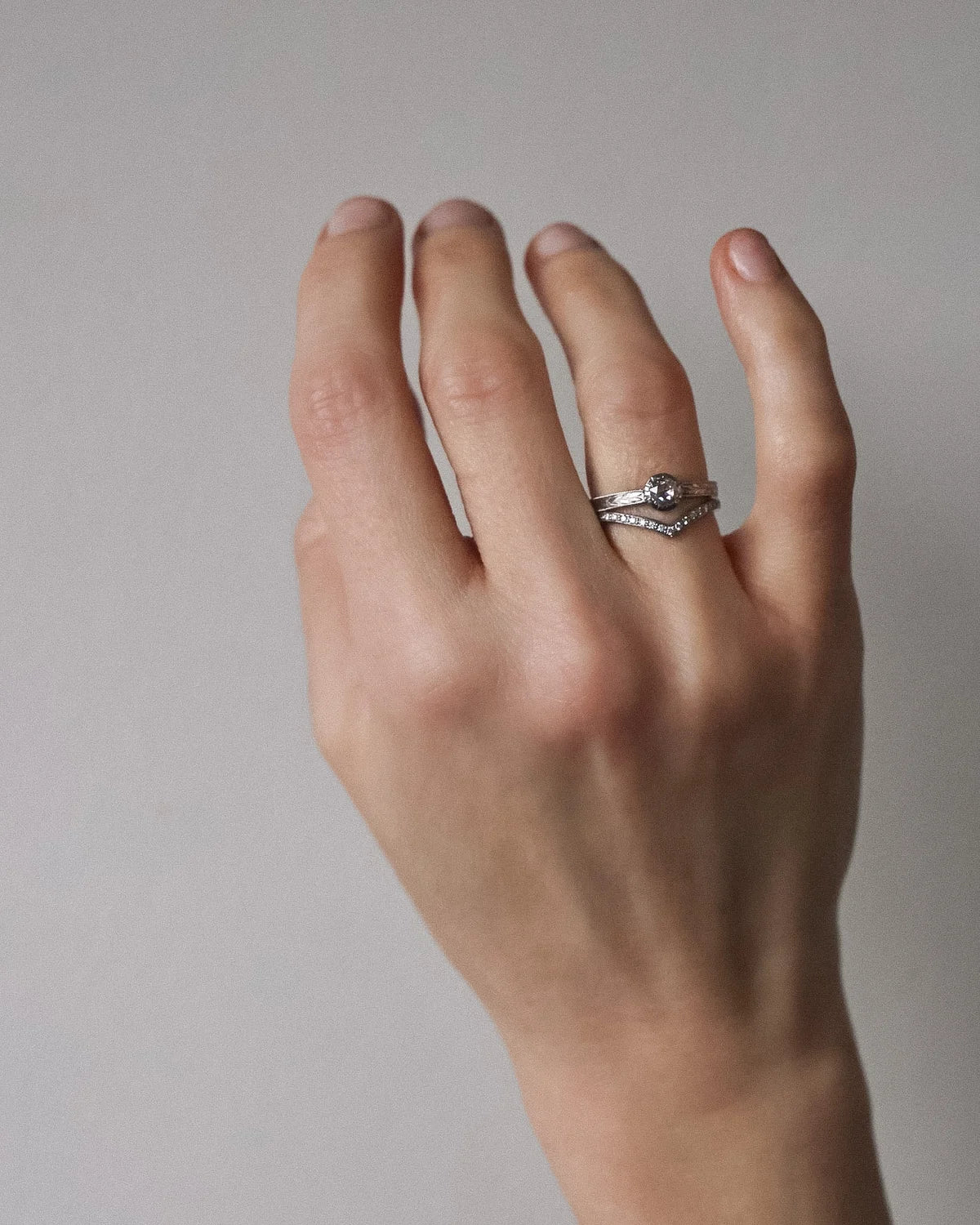 Woman wearing a handmade platinum rose-cut diamond engagement ring with matching pavé wishbone wedding band.