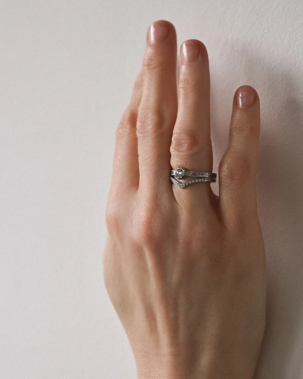 Woman wearing a handmade platinum rose-cut diamond engagement ring with matching pavé wishbone wedding band.