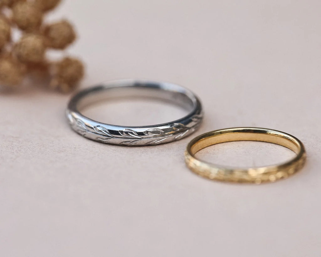 Platinum and yellow gold olive leaf wedding rings styled with dried flowers
