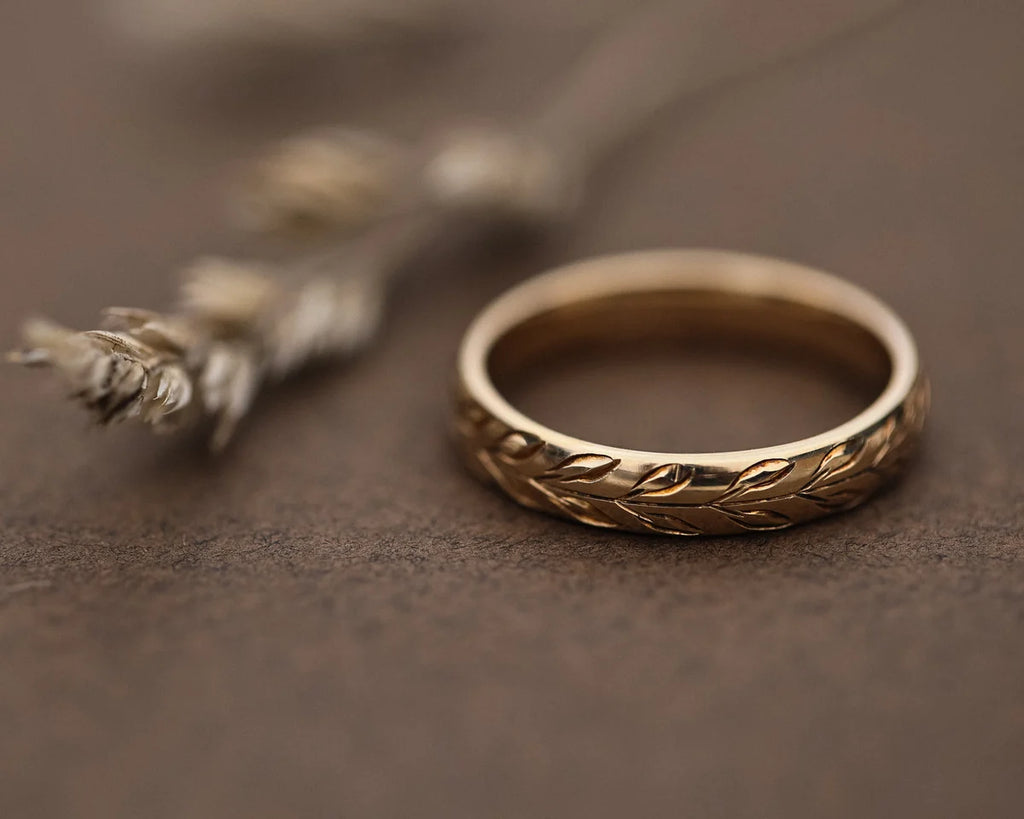 Close-up of 9ct yellow gold olive leaf engraved court wedding ring