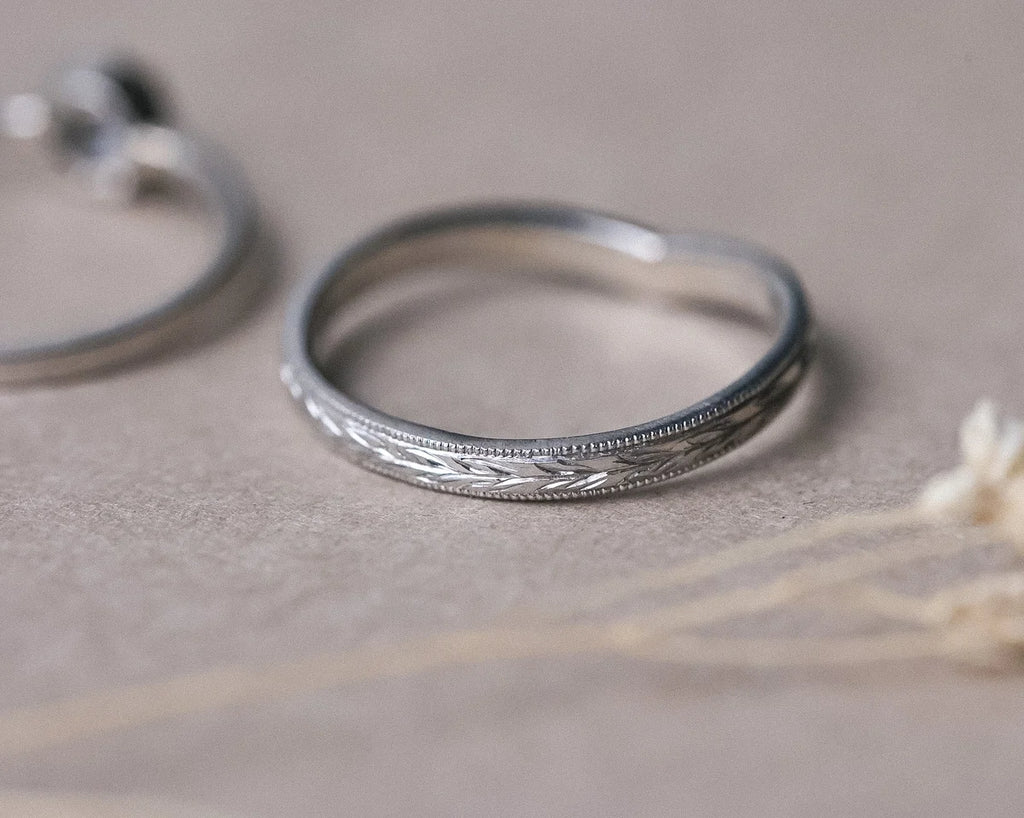 Close-up of olive leaf engraving and milled edge on platinum wishbone ring