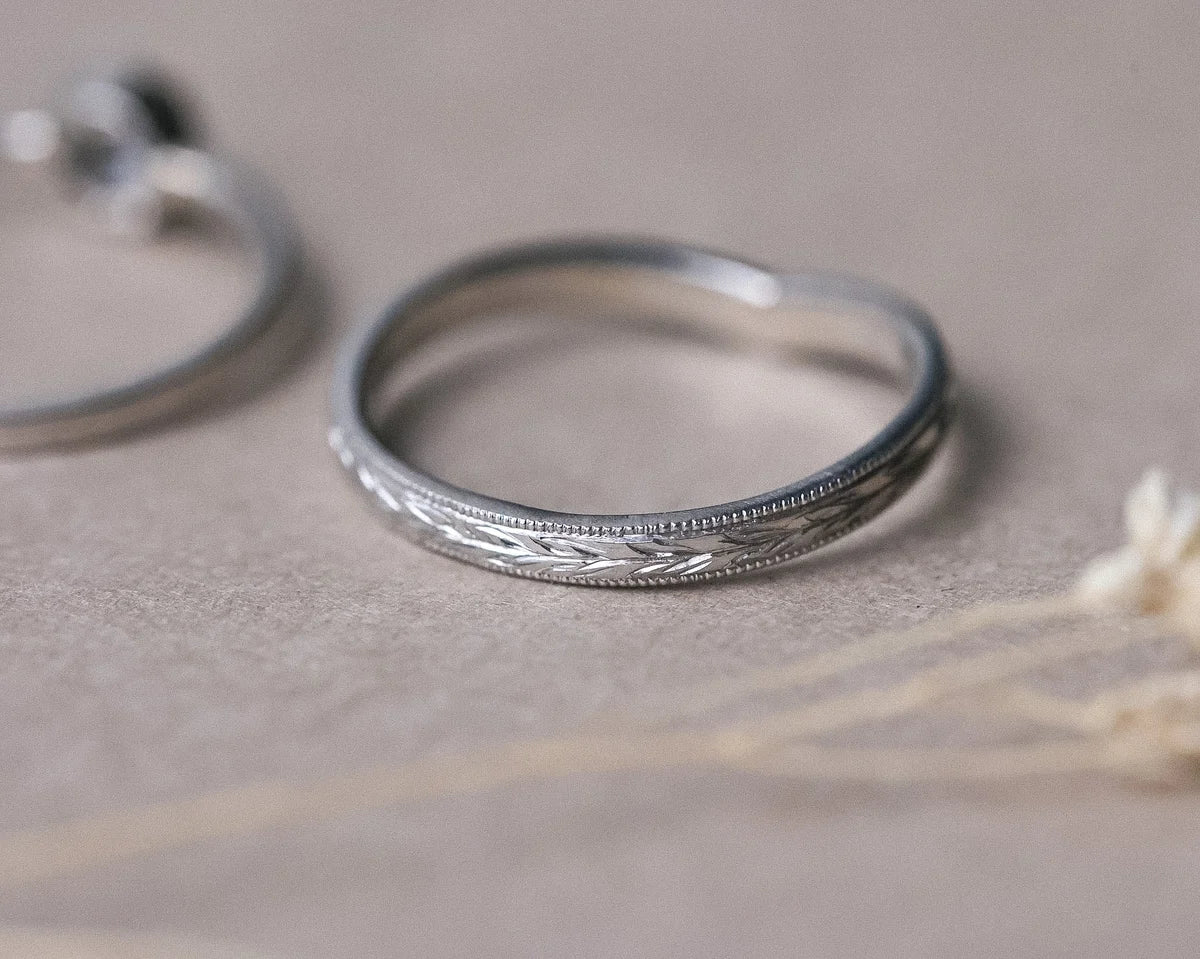 Close-up of olive leaf engraving and milled edge on platinum wishbone ring