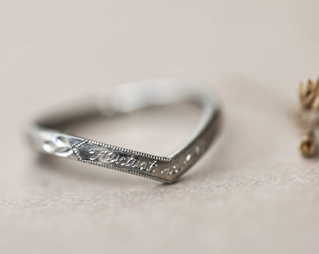 Silver ring with engraved text on a beige background