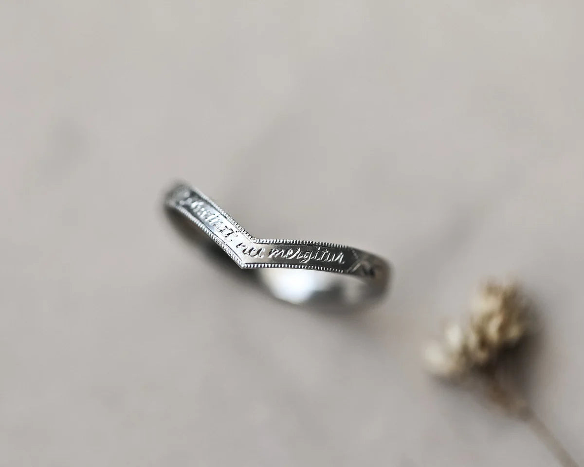 Silver ring with engraved text on a light gray background