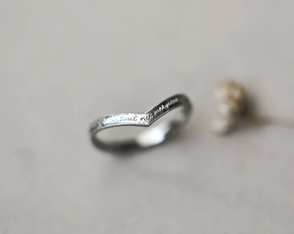 Silver ring with engraved text on a neutral background