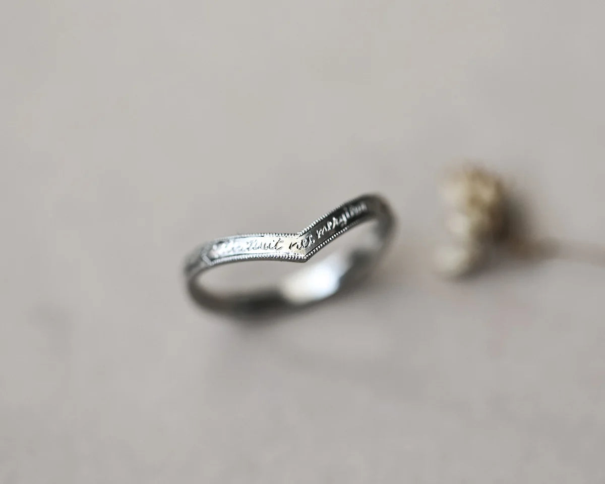 Silver ring with engraved text on a neutral background