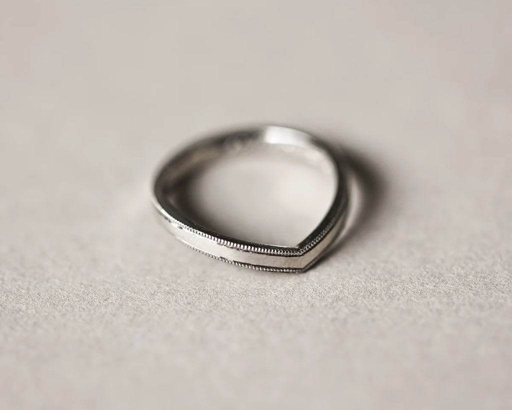 Angled view of handmade platinum wishbone ring with fine milled edge
