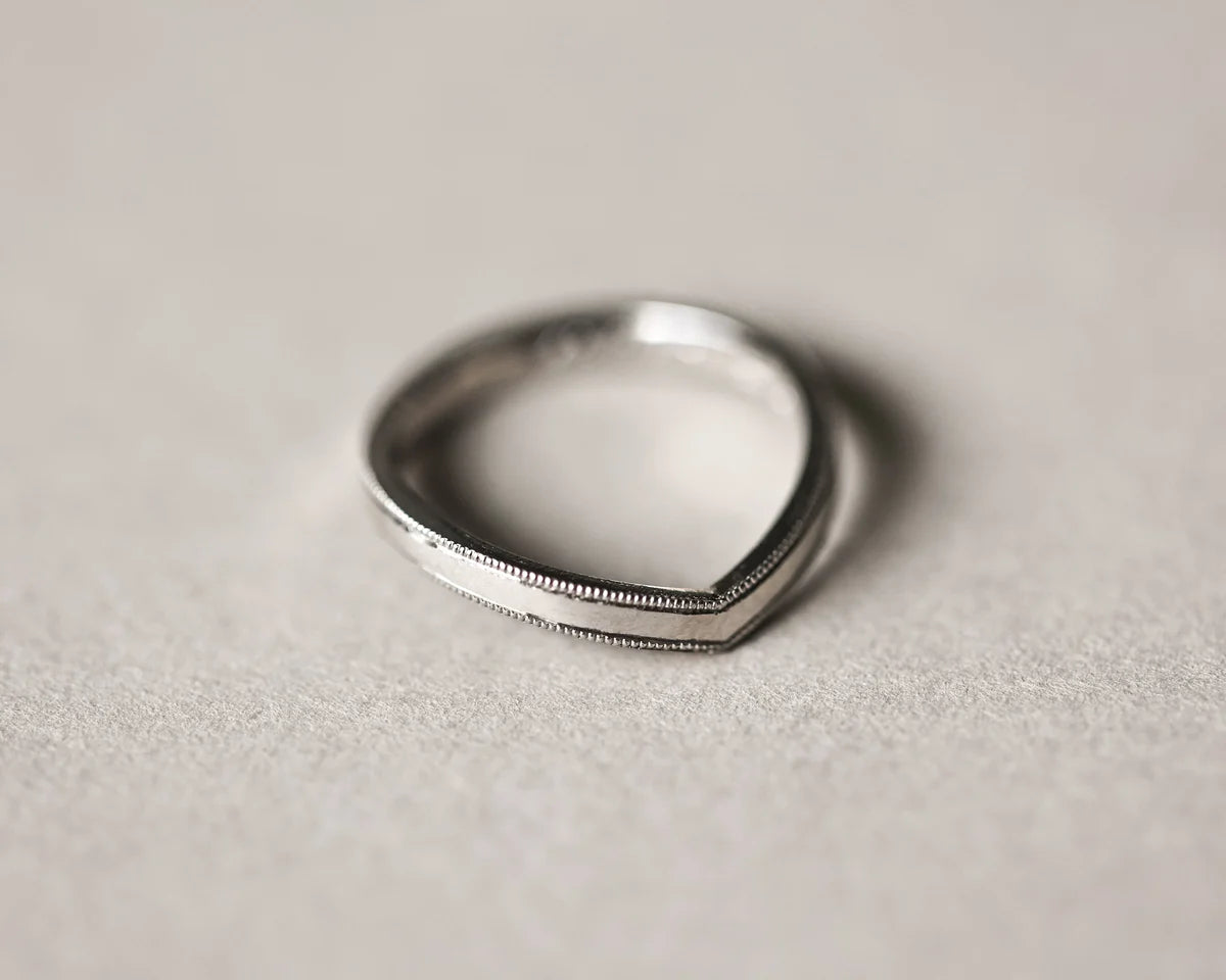 Angled view of handmade platinum wishbone ring with fine milled edge