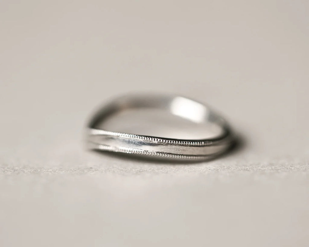 Side view of platinum wishbone ring with hand engraved milled edge