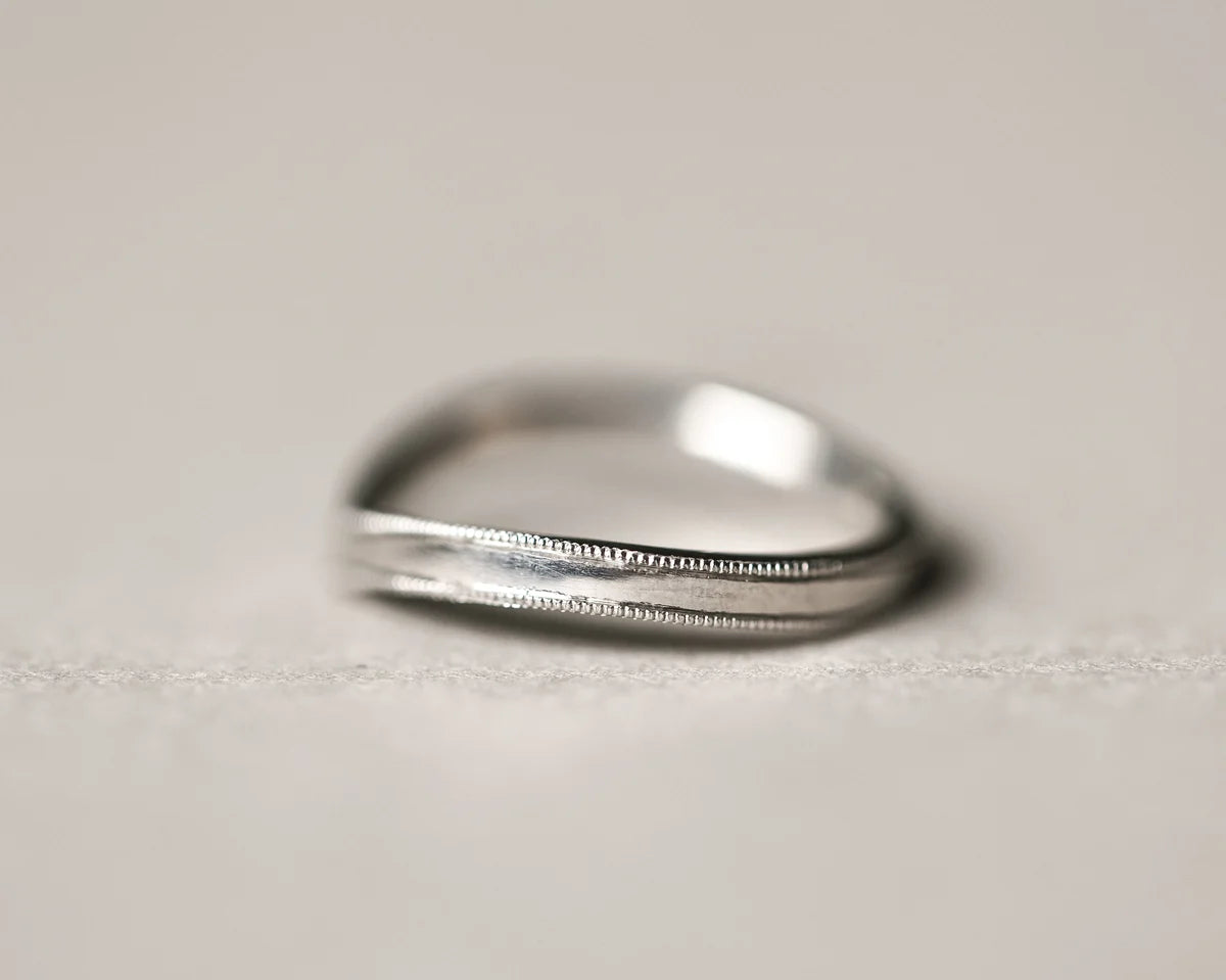 Side view of platinum wishbone ring with hand engraved milled edge