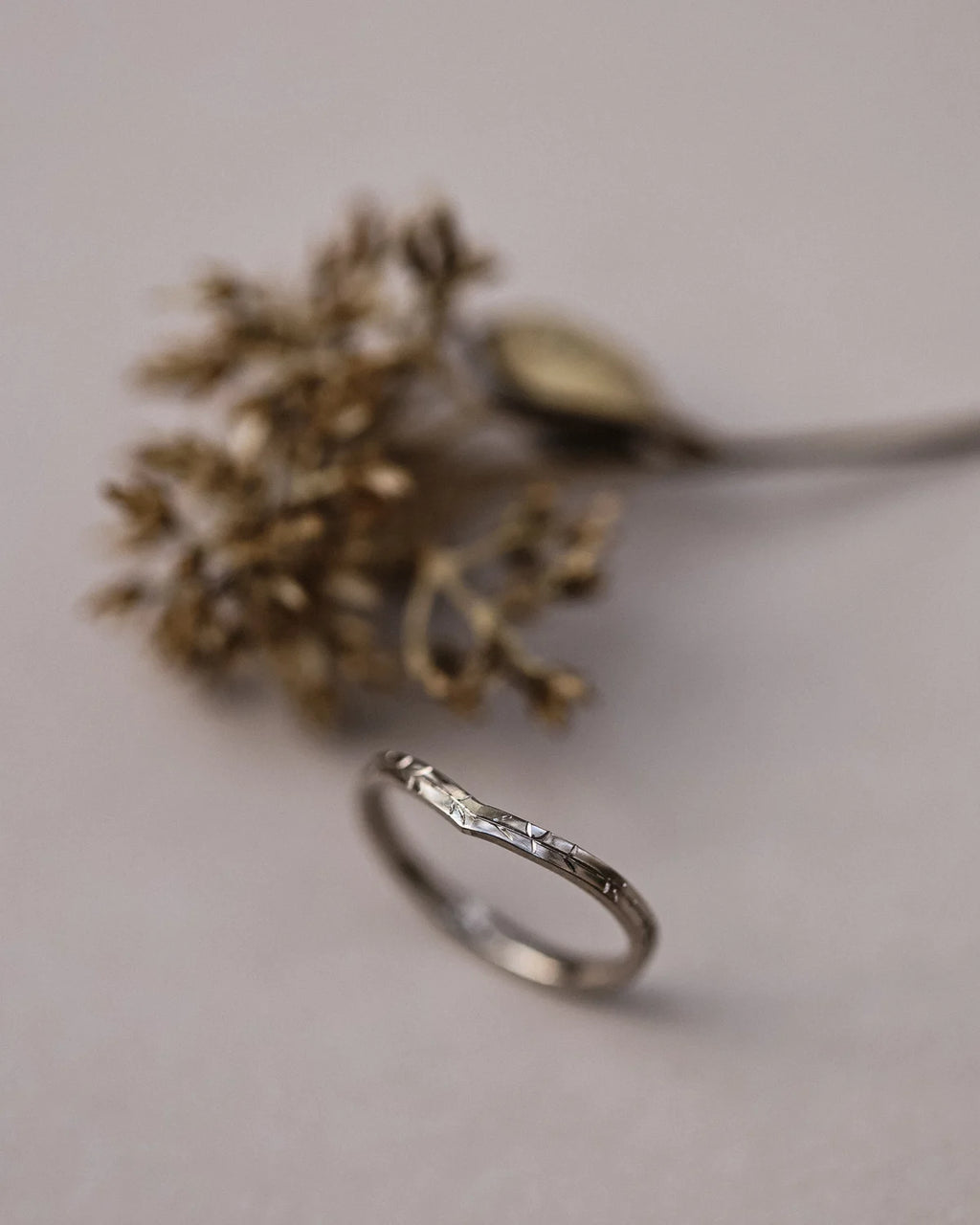 Vertical view of white gold willow leaf engraved wishbone ring